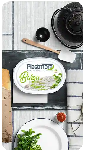 Gerçekçi bir kahvaltı masası üzerinde, kuşbakışı (flat lay) bir sahnede sunulan, yüksek kaliteli 3D görselleştirmesi ve ürün maketiyle Plastmore Burgu Peyniri ambalajı.